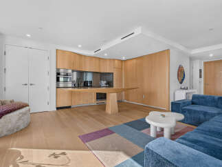 Experience modern living in this open-concept space featuring a sleek kitchen with integrated appliances and ample wood cabinetry.