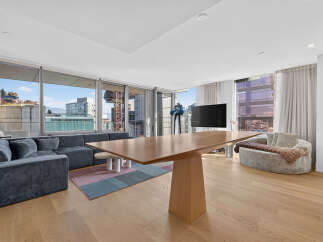 Experience modern living in this spacious open-concept apartment, featuring a large sectional sofa and a sleek dining table perfect for entertaining.