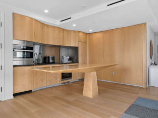 Experience modern luxury in this sleek kitchen featuring custom light wood cabinetry that curves seamlessly around the space.