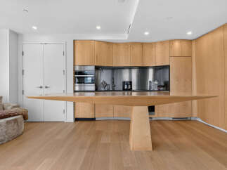 Experience modern living in this stunning kitchen featuring sleek, light wood cabinetry that extends to the ceiling.