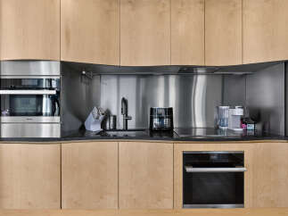 Experience modern luxury in this sleek kitchen, featuring integrated Miele appliances including a built-in oven and microwave.