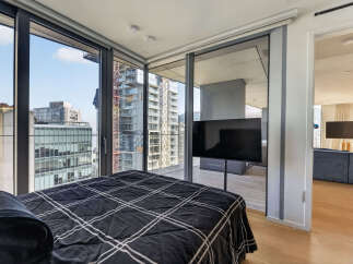 Experience urban living at its finest in this stunning bedroom featuring expansive floor-to-ceiling windows that offer breathtaking city views.