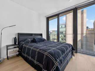 Experience modern urban living in this stylish bedroom featuring a comfortable bed with a striking plaid comforter.