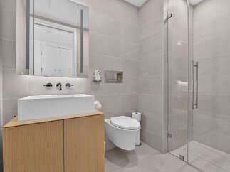 Experience modern luxury in this stunning bathroom, featuring a sleek vessel sink atop a warm wood vanity.