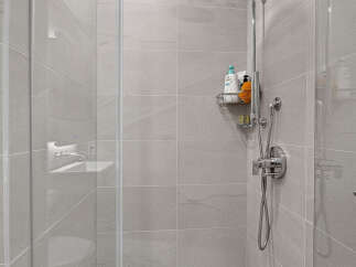 Step into this modern shower featuring a sleek, minimalist design with large format grey tiles on the walls and floor.