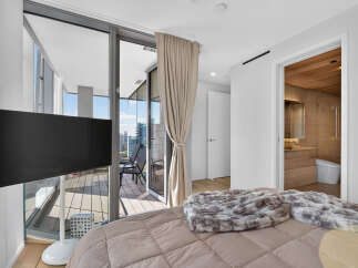 Experience luxury living in this stunning bedroom featuring a plush bed with a cozy throw blanket.