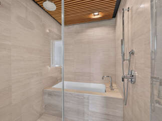 Experience modern luxury in this stunning bathroom featuring a deep soaking tub and a separate rainfall shower.