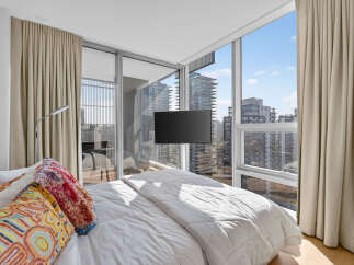 Experience luxury urban living in this stunning bedroom featuring floor-to-ceiling windows that offer breathtaking city views.