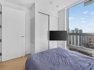 Experience modern urban living in this stylish bedroom, featuring a comfortable bed dressed in a serene blue comforter.