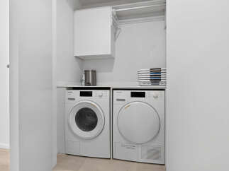 This laundry room features a stacked Miele washer and dryer set, ensuring efficient and high-quality garment care.