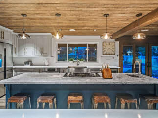 Experience luxury in this stunning kitchen featuring a spacious island with a granite countertop and comfortable bar stools.