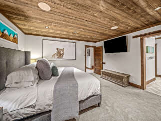 Experience rustic luxury in this master bedroom, featuring a plush king-sized bed adorned with crisp white linens and accented by a cozy knit throw.