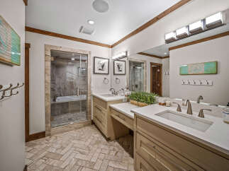 This luxurious bathroom features a spacious walk-in shower with a soaking tub, complemented by a double vanity with ample counter space and storage.