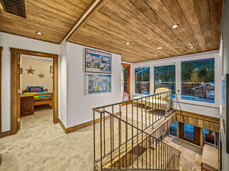 Experience the charm of this mountain retreat, featuring a rustic wood-paneled ceiling and a cozy hallway leading to a bedroom.