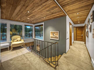 Experience rustic charm and modern comfort in this stunning home featuring a beautifully paneled wood ceiling and a spacious hallway.