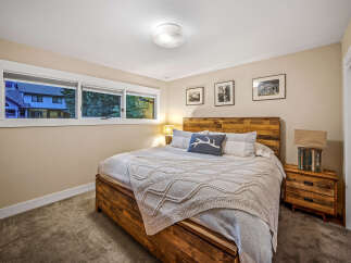 This cozy bedroom features a rustic wooden bed frame and headboard, complemented by a plush knit blanket and decorative pillows.