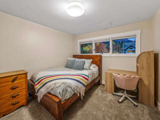 This cozy bedroom features a comfortable wooden bed adorned with a colorful striped blanket and plush pillows.