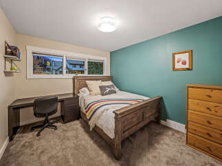 This cozy bedroom features a rustic wooden bed adorned with a striped blanket and decorative pillows.
