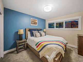 This cozy bedroom features a comfortable queen-size bed adorned with a classic striped blanket and plush pillows.