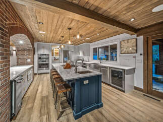 Experience luxury in this stunning kitchen featuring a large island with seating, sleek granite countertops, and a wine fridge.