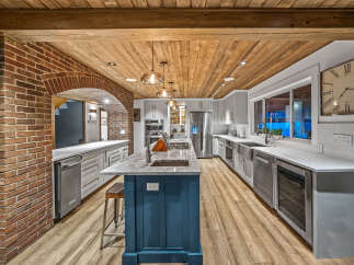 Experience luxury in this stunning kitchen, featuring a striking brick archway and a warm, wood-planked ceiling.