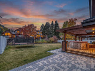 Experience luxury living with this stunning backyard oasis, featuring a rustic wooden hot tub perfect for relaxation under the twilight sky.