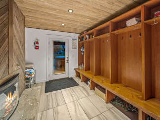 Step into a cozy and functional mudroom featuring a warm fireplace and convenient locker storage.
