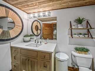 This rustic bathroom features a charming wooden vanity with ample storage and a sleek white countertop.