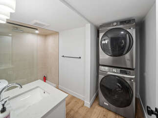 This modern bathroom features a sleek vanity with a white countertop and sink, complemented by a stylish chrome faucet.