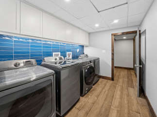 This laundry room boasts a sleek design with a vibrant blue subway tile backsplash that adds a pop of color to the space.