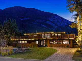 Experience luxury living in this stunning mountain-view home, beautifully illuminated by festive string lights.