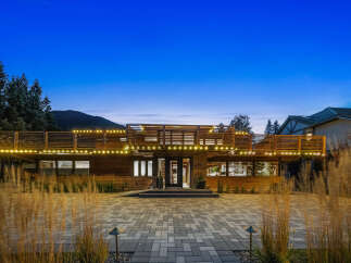 Experience modern luxury in this stunning home, featuring a sleek wooden exterior and expansive multi-level decks perfect for entertaining.