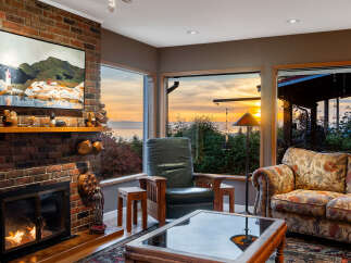 Experience breathtaking sunset views from this cozy living room, featuring a warm brick fireplace and comfortable seating.