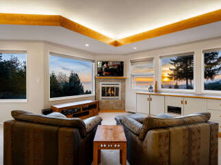Experience breathtaking sunset views from this stunning living room, featuring a cozy fireplace and a large entertainment center.
