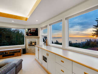 Experience breathtaking ocean views from this stunning living room, featuring a cozy fireplace and a large entertainment center.