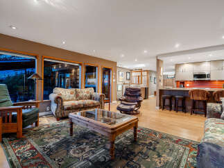 This spacious open-concept living area features a cozy seating arrangement with a floral-patterned sofa and a leather recliner, complemented by a large oriental rug.