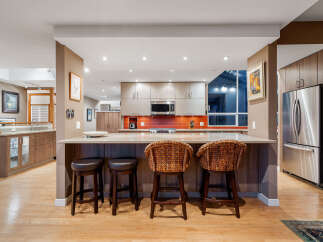 This modern kitchen boasts sleek cabinetry and a vibrant orange tiled backsplash, creating a stylish and functional space.