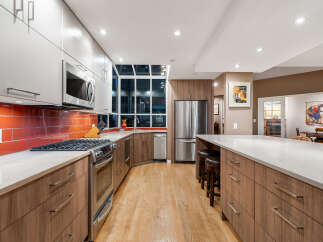 Experience modern luxury in this stunning kitchen, featuring sleek grey cabinetry, a vibrant orange tiled backsplash, and a spacious island perfect for entertaining.