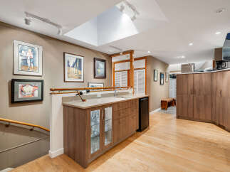 This inviting finished basement features a stylish wet bar with ample cabinet storage, a mini-fridge, and a sink, perfect for entertaining.