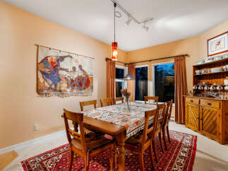 This inviting dining room features a warm peach-colored accent wall adorned with a vibrant tapestry, creating a cozy and artistic atmosphere.