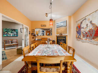 This dining room features a warm and inviting atmosphere with its peach-colored walls and a large wooden dining table set with a decorative tablecloth.