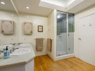 This spacious bathroom features a double vanity with modern chrome fixtures, complemented by two wooden medicine cabinets with unique turquoise accents.