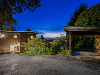 Experience breathtaking sunset views from this stunning property, featuring a unique architectural design with shingle siding and a modern aesthetic.