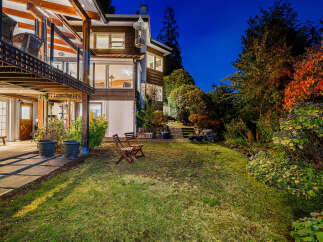 Enjoy the evening ambiance from this stunning property's backyard, featuring a lush green lawn perfect for relaxation and play.