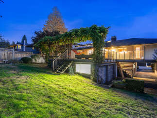 This stunning property features a multi-level backyard with a lush green lawn, perfect for outdoor activities.