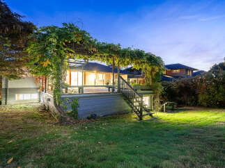 Enjoy evenings on this expansive deck, shaded by a lush green pergola, perfect for outdoor entertaining.