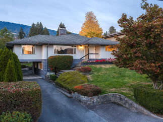 Discover this charming home nestled amidst a picturesque landscape, featuring a well-maintained lawn and mature trees.