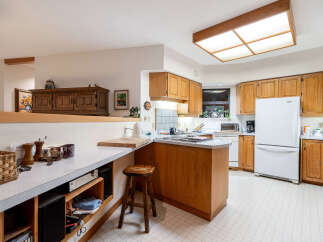 This spacious kitchen boasts ample natural light, complemented by warm wooden cabinetry and a functional island.