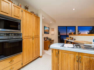 Experience breathtaking sunset views from this stunning kitchen, featuring a built-in oven and microwave, ample cabinet space, and a sleek stovetop.
