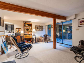 Discover a versatile living space with a cozy reading nook featuring a plush recliner and a well-stocked bookshelf.